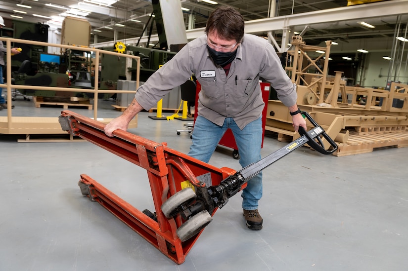 Photo of Darren Stout examining a pallet jack.