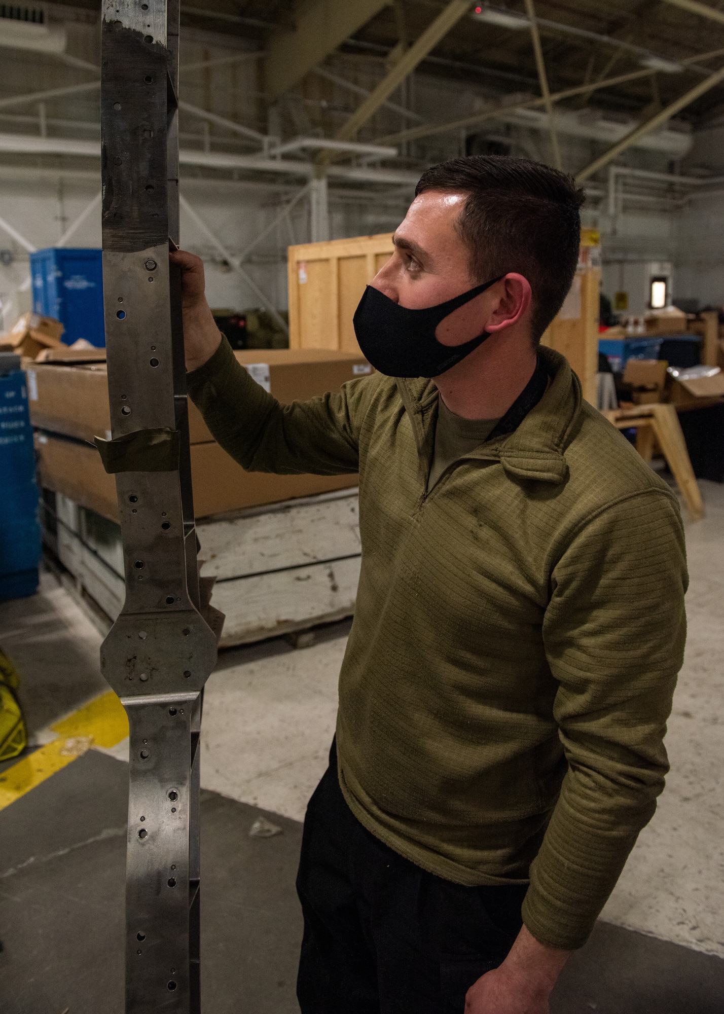 An Airman holds up a damaged part from an F-22 aircraft.