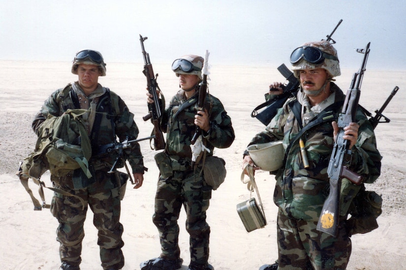 Four Marines hold up weapons.