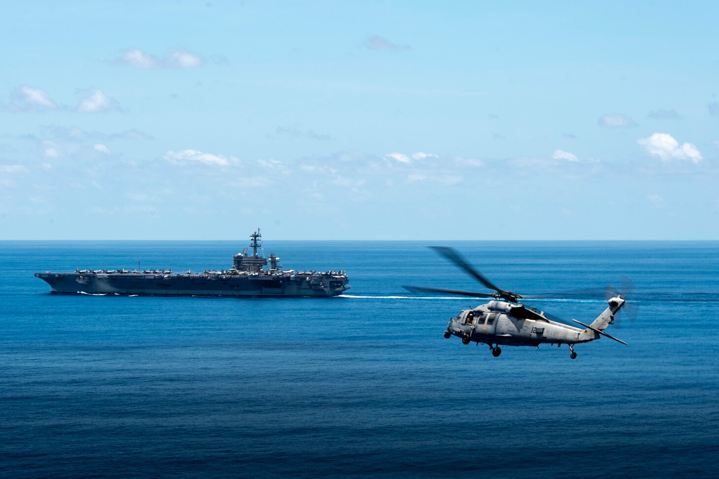 INDIAN OCEAN (Dec. 17, 2021) An MH-60S Sea Hawk, assigned to the “Black Knights” of Helicopter Sea Combat Squadron (HSC) 4, flies next to Nimitz-class aircraft carrier USS Carl Vinson (CVN 70) while transiting the Indian Ocean during a bilateral training exercise with the Royal Australian Air Force, Dec. 17, 2021. Carl Vinson Carrier Strike Group and elements of the Royal Australian Navy and Air Force are conducting a bilateral training exercise to test and refine warfighting capabilities in support of a free and open Indo-Pacific. (U.S. Navy photo by Mass Communication Specialist 2nd Class Haydn N. Smith)