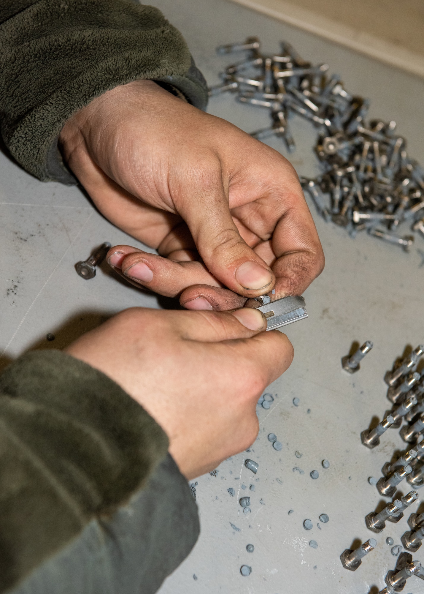 Airmen prepares fasteners for installation during the rebuild of an F-22 aircraft.