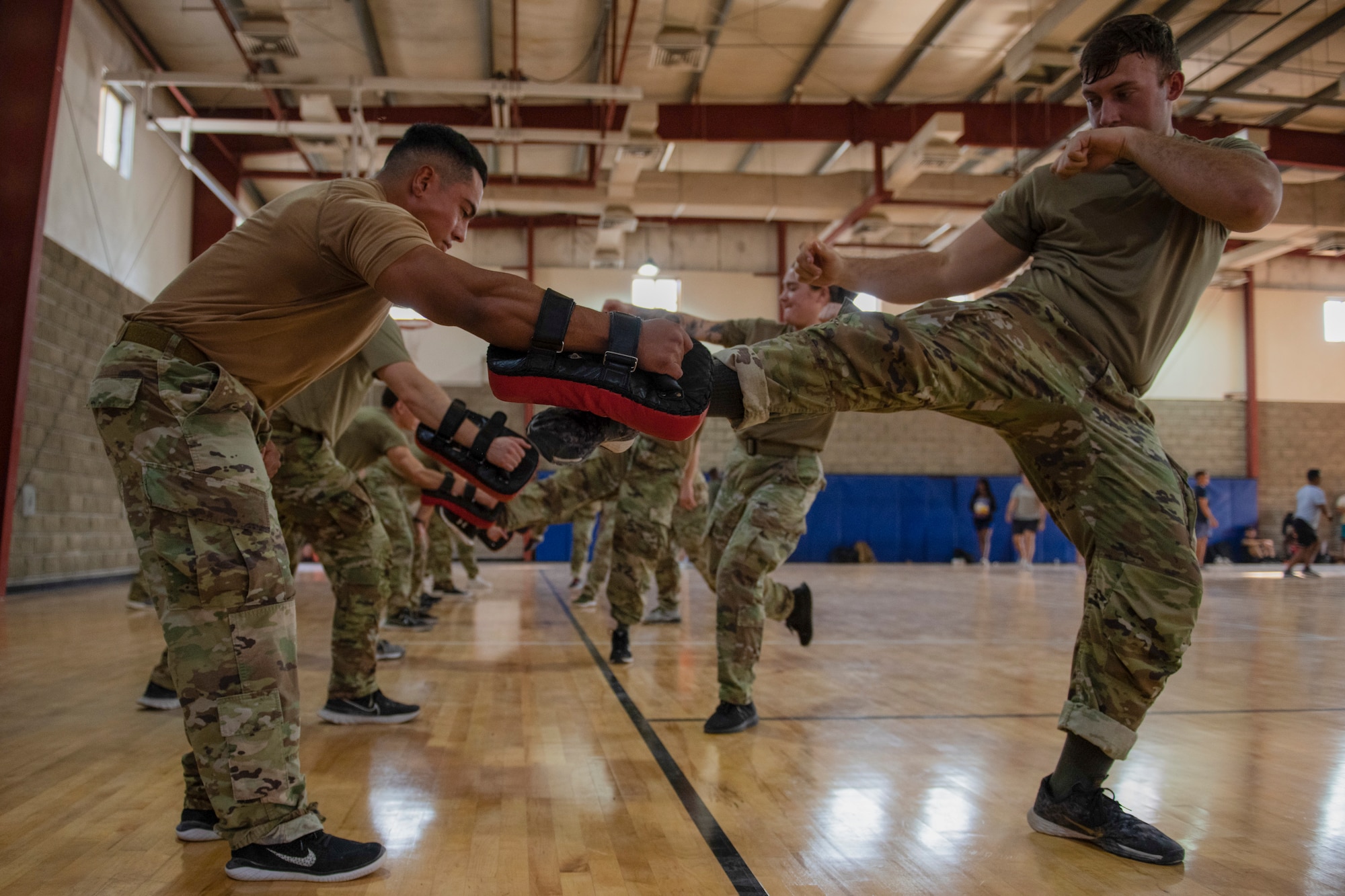 Airmen kick pad doing martial arts.