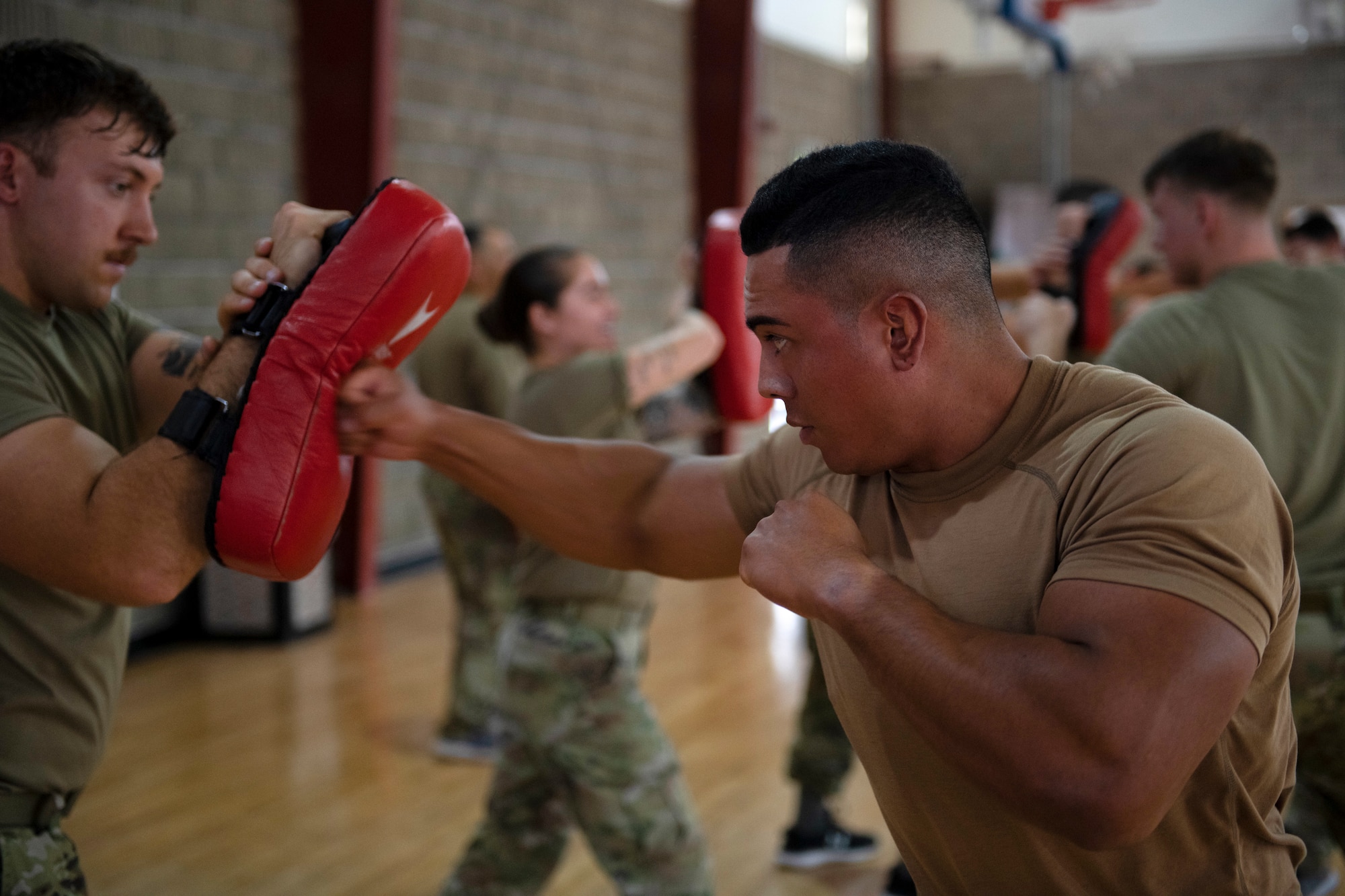 Airmen punch pads during martial arts training.