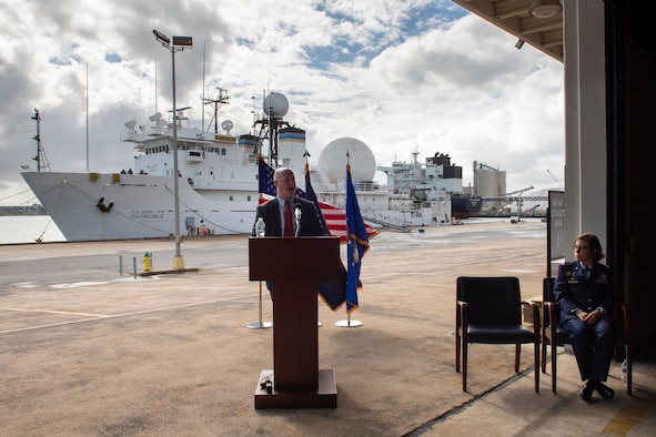 Christopher Thayer, Director of Maritime Operations for Military Sealift Command, delivers his keynote address during the Inactivation Ceremony of the U.S. Naval Ship Invincible (seen in background) at Cape Canaveral Space Force Station, Fla., Dec. 15, 2021.  Pictured to the right is Col. Katharine Branson, commander of the Air Force Technical Applications Center, overseer of the Invincible's GRAY STAR ballistic missile radar system.  (U.S. Air Force photo by Matthew S. Jurgens)