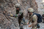 U.S. Army Staff Sgt. Elijah Amendola, 1-102nd Infantry Regiment (Mountain), Task Force Iron Gray, Combined Joint Task Force – Horn of Africa (CJTF-HOA), assists a French service member with the 5th Overseas Interarms Regiment (5e RIAOM) on fixed rope techniques at the Arta Range Complex, Djibouti, Dec. 15, 2021. Five instructors from the U.S. Army Mountain Warfare School in Jericho, Vermont, taught a five-day Joint Expeditionary Mountain Warfare Course on basic military mountaineering skills to French service members in Djibouti to strengthen the relationships among the international forces working together in the region.