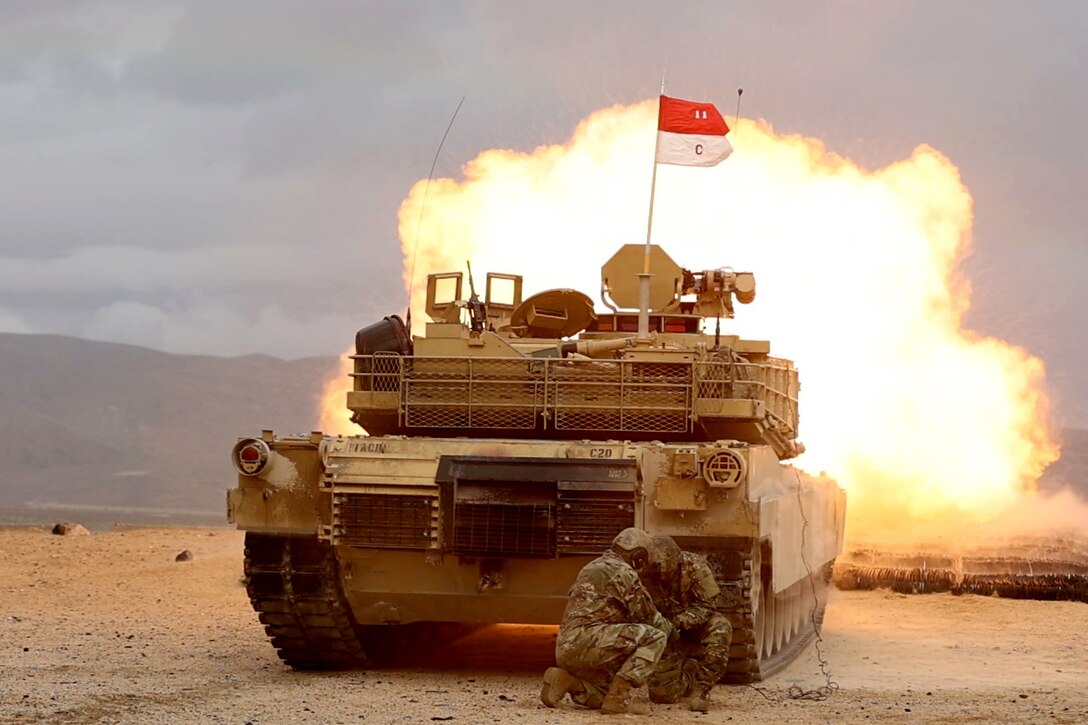 A tank fires a round with a large fireball coming from the barrel of the tank.