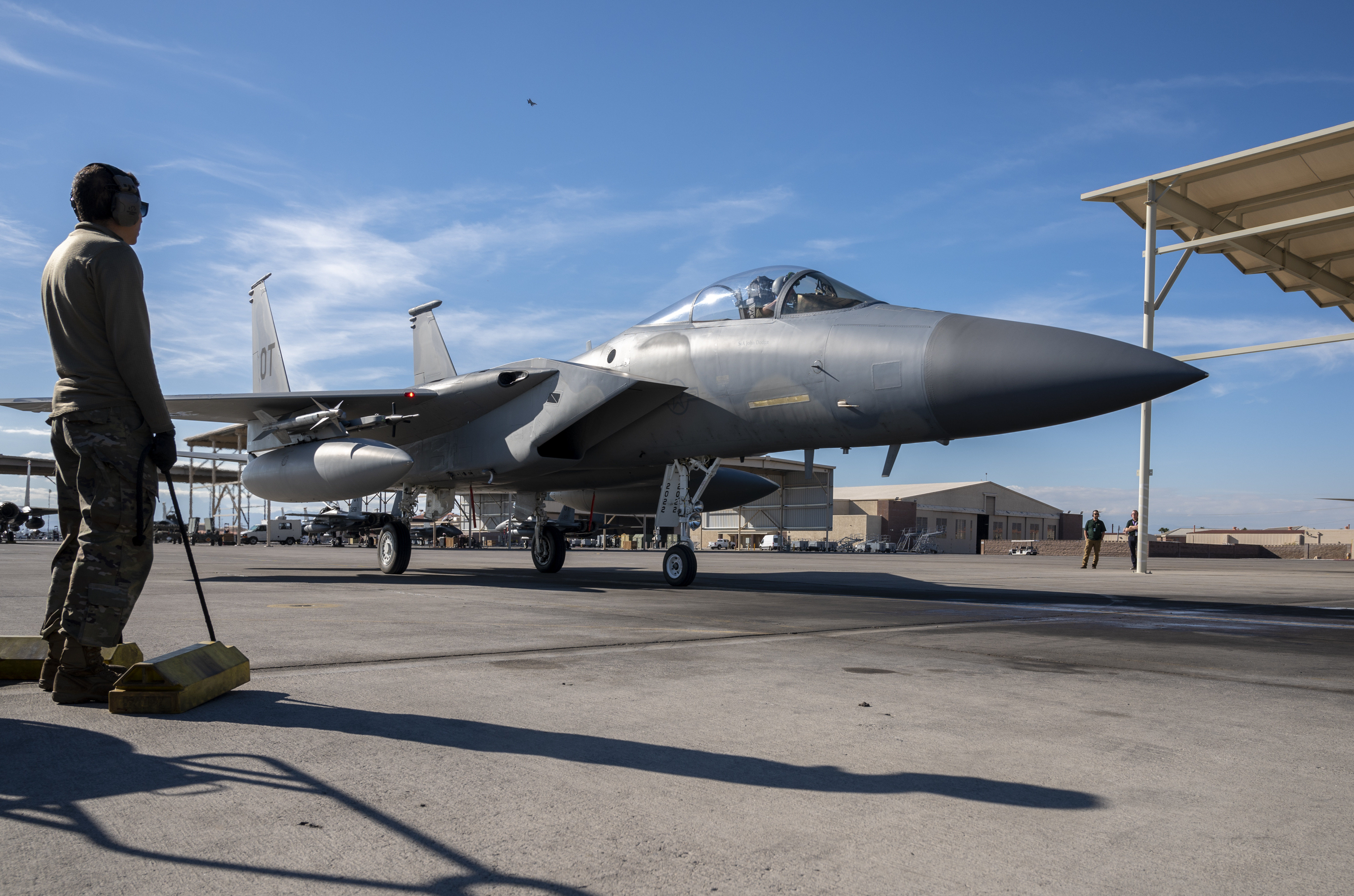 A maintainer removes the chocks from an F-15C Eagle as it prepares to take off to conduct its final defensive counter air vul during Weapons School Integration 21-B at Nellis Air Force Base, Nevada, Dec. 8, 2021. Maintainers have kept the F-15C Eagle flying since 1978.