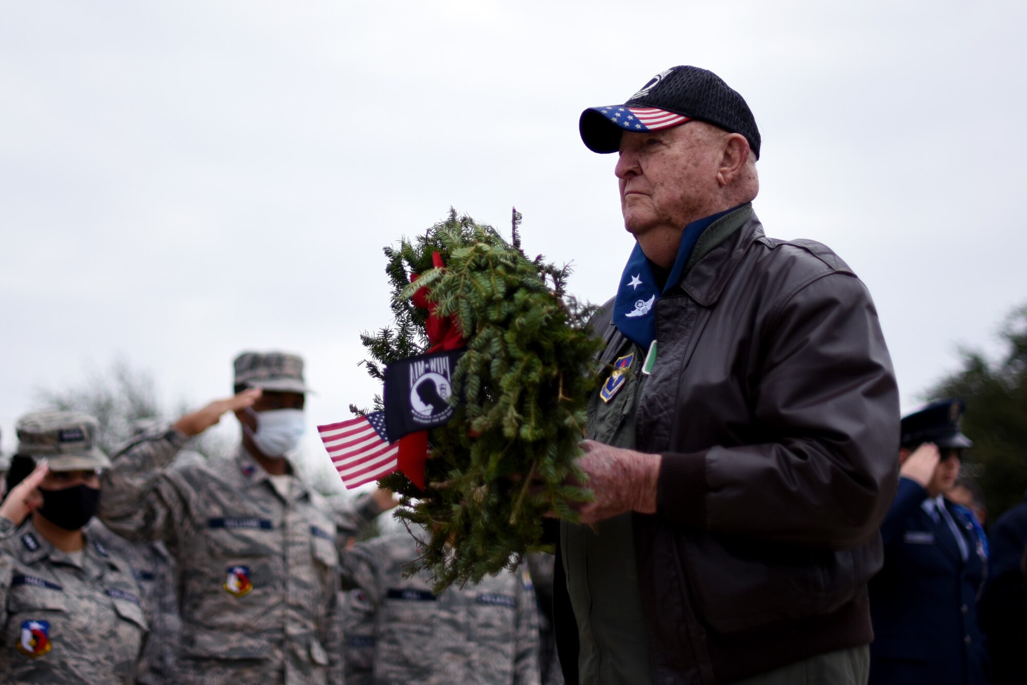 Col. John Yuill, retired, carries the Prisoner of War wreath during a Wreaths Across America event at the Dallas-Fort Worth National Cemetery on Dec. 18, 2021. Yuill was interned as a Prisoner of War in North Vietnam after he was shot down on December 22, 1972 and was held until his release on March 29, 1973. (U.S. Air Force photo by Staff Sgt. Randall Moose)