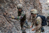 U.S. Army Staff Sgt. Elijah Amendola, 1-102nd Infantry Regiment (Mountain), Task Force Iron Gray, Combined Joint Task Force – Horn of Africa (CJTF-HOA), assists a French service member with the 5th Overseas Interarms Regiment (5e RIAOM) on fixed rope techniques at the Arta Range Complex, Djibouti, Dec. 15, 2021. Five instructors from the U.S. Army Mountain Warfare School in Jericho, Vermont, taught a five-day Joint Expeditionary Mountain Warfare Course on basic military mountaineering skills to French service members in Djibouti to strengthen the relationships among the international forces working together in the region.