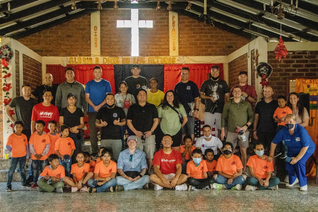 People sit and stand for a group photo in a room.