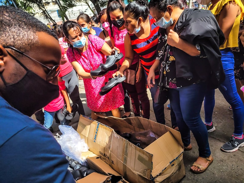 People pick shoes out of a cardboard box.