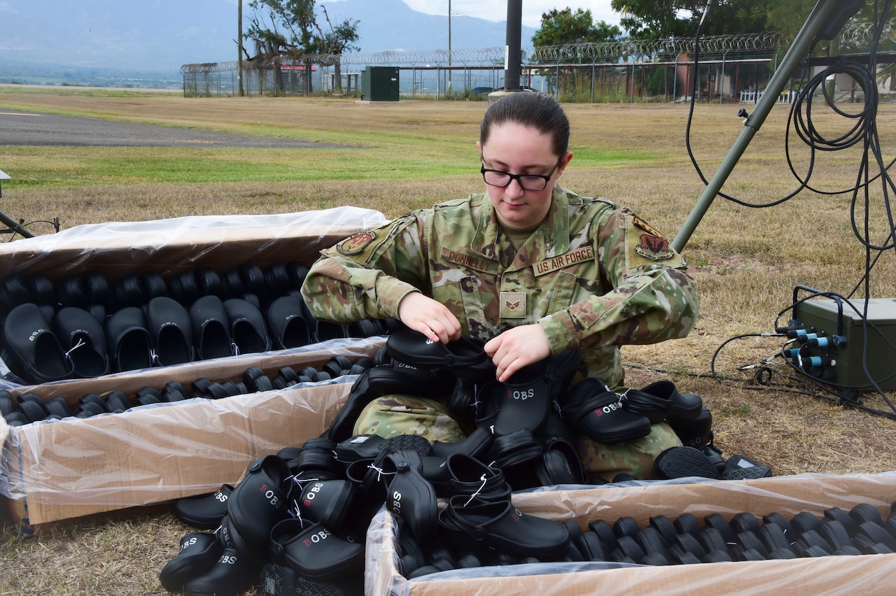 An airman organizes shoes outside.