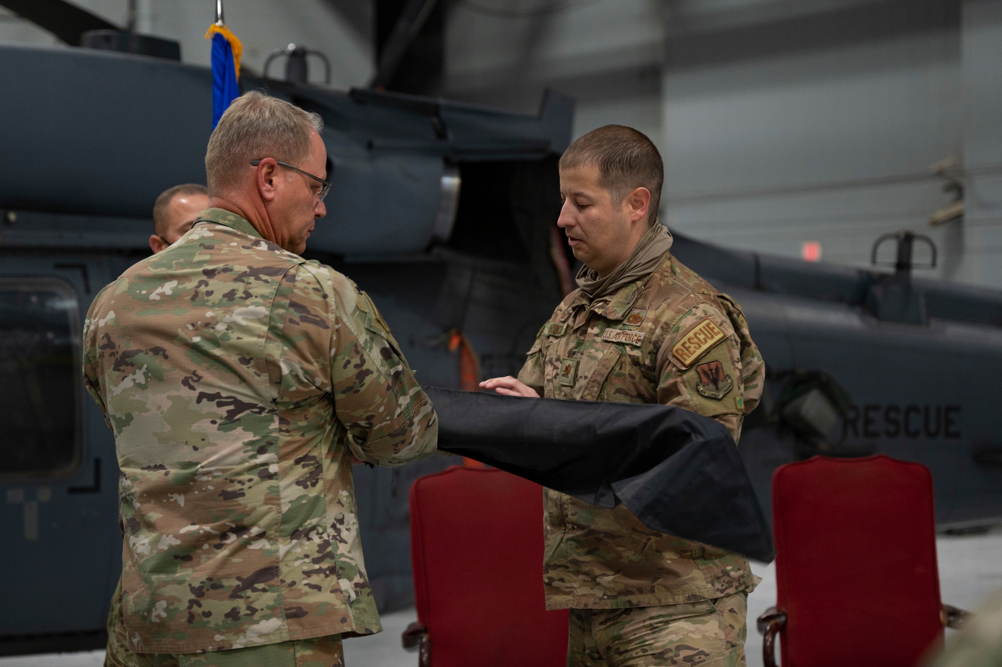 Two Airmen sheathing a flag.