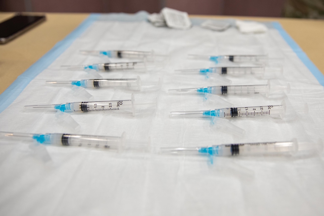 Syringes are stacked up on a tray.