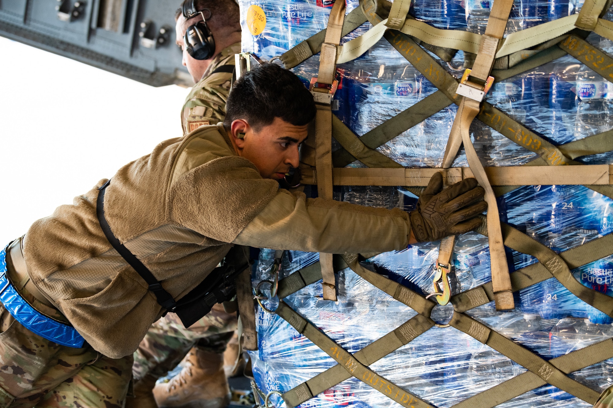 Airmen pushes a pallet of water onto an aircraft.