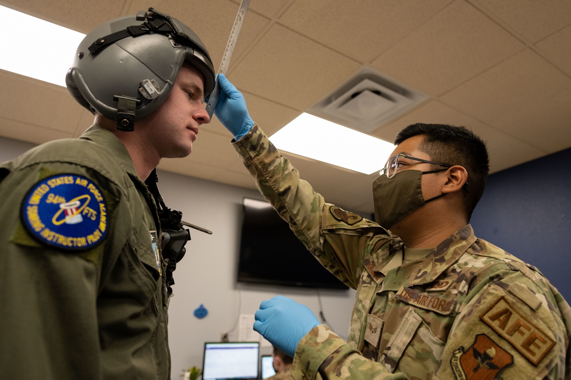 Senior Airman Andrew Ramirez, 54th Operations Support Squadron aircrew flight equipment journeyman, fits Blake Harrison, U.S. Air Force Academy cadet, for a helmet Dec. 15, 2021, on Holloman Air Force Base, New Mexico. Harrison, and other USAFA cadets, were offered familiarization flights in F-16 Vipers to better orient them with the mission and job of a fighter pilot. (U.S. Air Force photo by Senior Airman Kristin Weathersby)