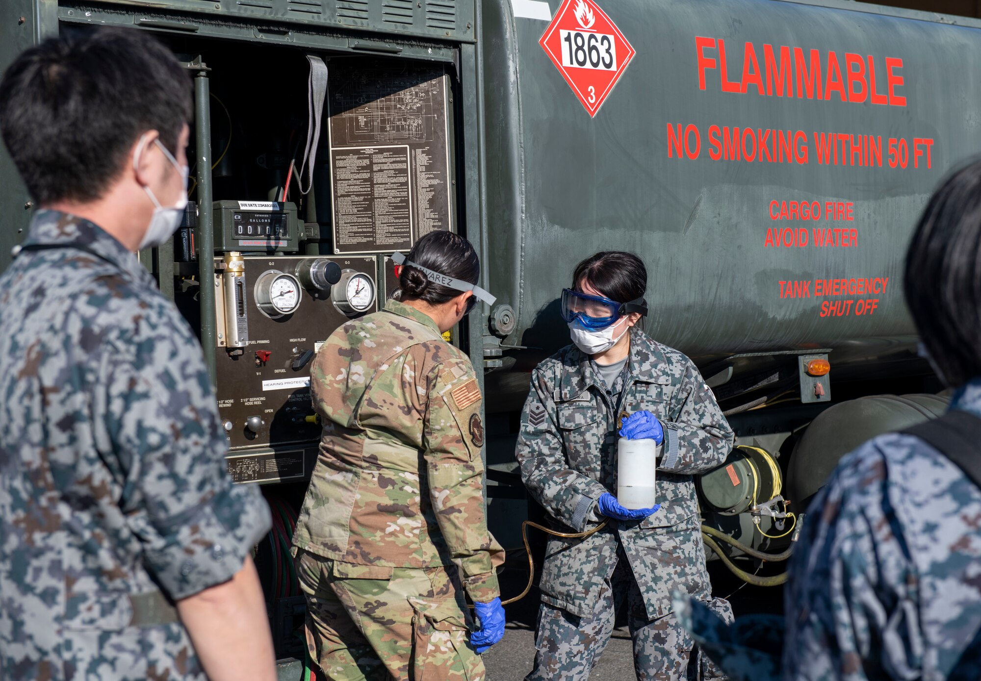 A U.S. Air Force Airman and Japan Air Self Defense Force member demonstrate taking a fuel sample from an R-11 refueling truck.