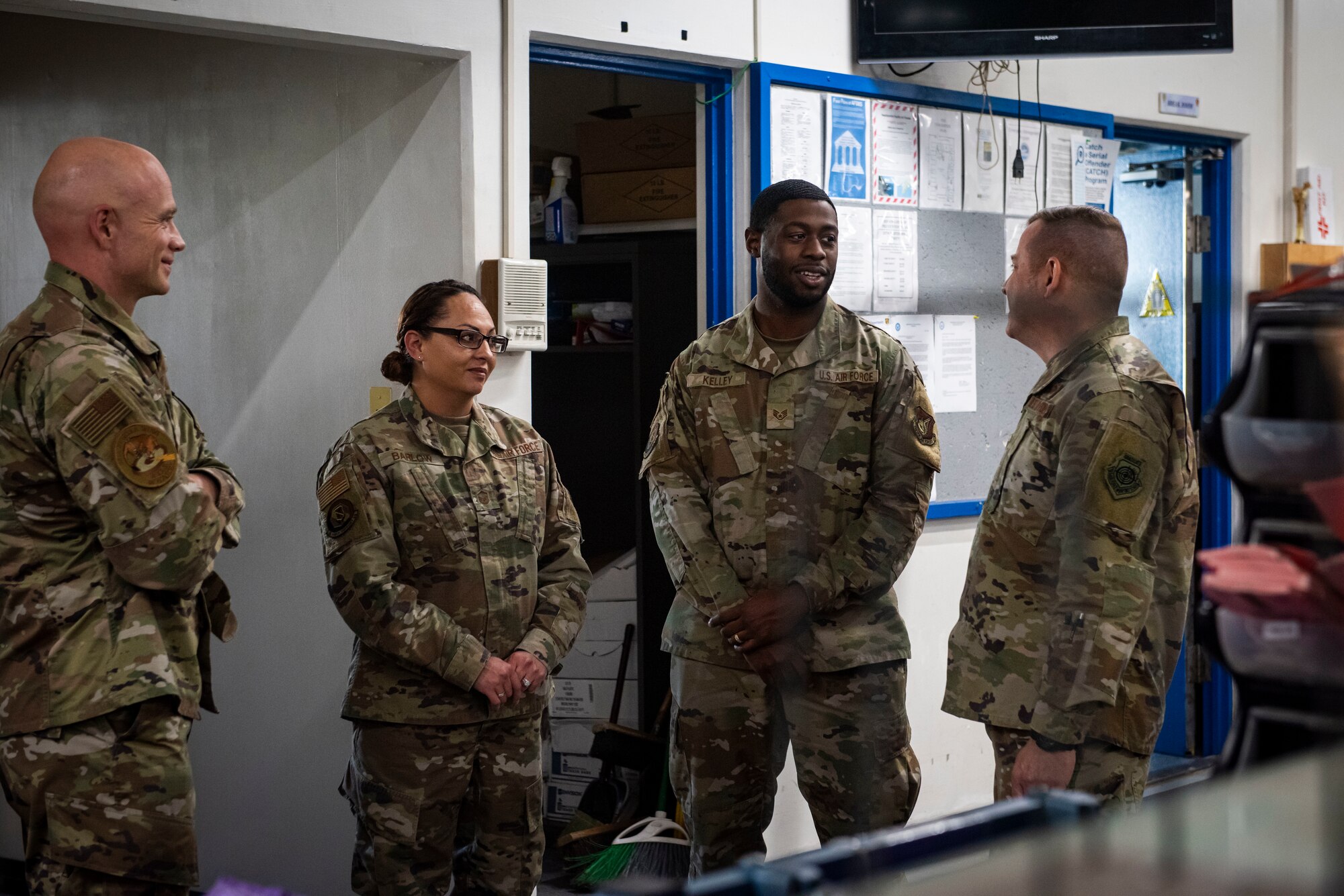 Group of military members in uniform talk in a post office.