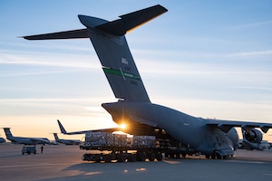Bottles of waters being loaded onto a C-17 aircraft during sunset.