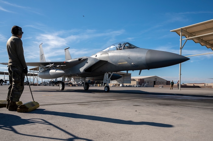 Airman holding chocks standing next to F-15C on ramp