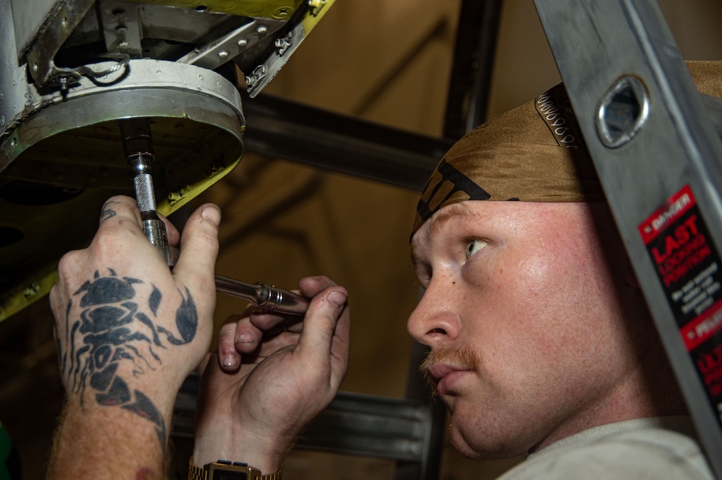 Aviation Structural Mechanic 3rd Class Kade Mckinney, from Wayland, Iowa, assigned to the "Seahawks" of Airborne Command and Control Squadron (VAW) 126, tightens rudder bolts of an E-2D Hawkeye in the hangar bay of the Nimitz-class aircraft carrier USS Harry S. Truman (CVN 75).