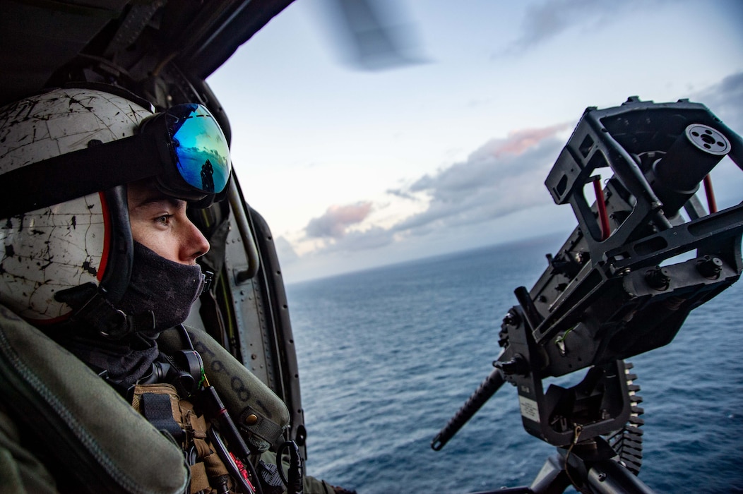 Naval Air Crewman (Helicopter) 1st Class Corey Furtado, from Plymouth, Massachusetts, assigned to the "Dragon Slayers" of Helicopter Sea Combat Squadron (HSC) 11, transits the Strait of Gibraltar in an MH-60S Sea Hawk helicopter, Dec. 14, 2021.