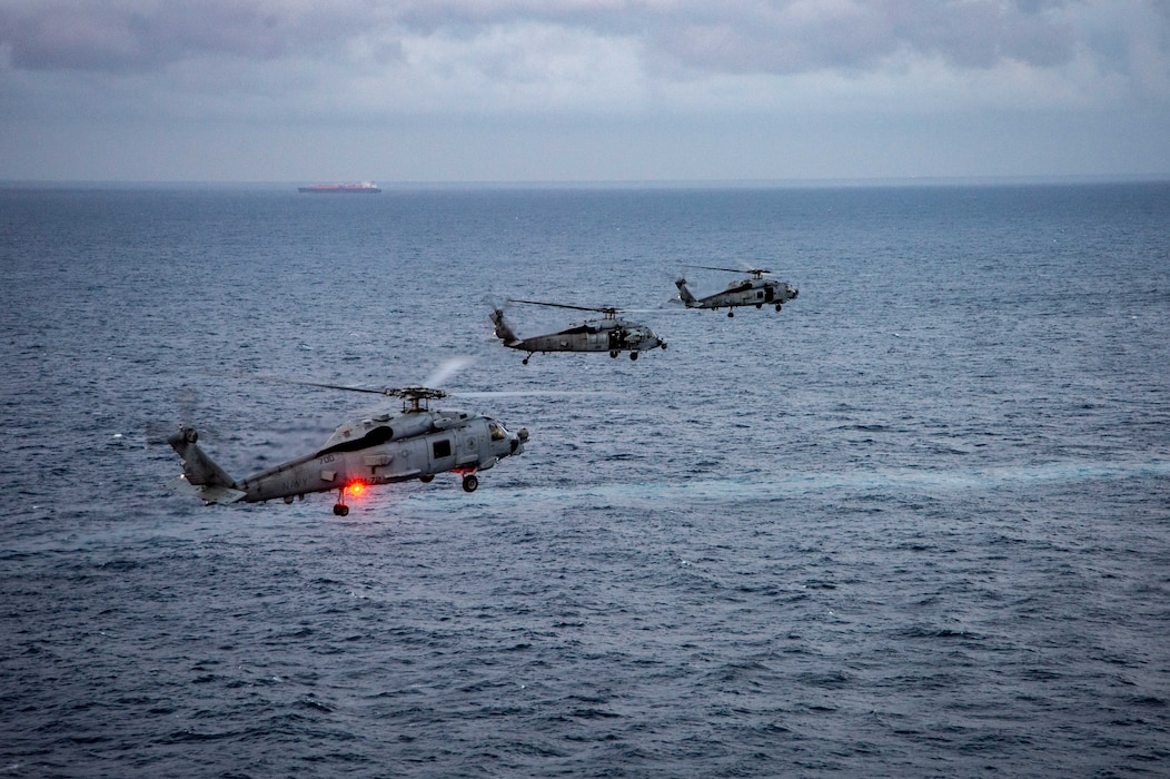 Two MH-60R Sea Hawk helicopters, attached to the "Proud Warriors" of Helicopter Maritime Strike Squadron (HSM) 72 and an MH-60S Sea Hawk helicopter, attached to the "Dragon Slayers" of Helicopter Sea Combat Squadron (HSC) 11, center, fly alongside the Nimitz-class aircraft carrier USS Harry S. Truman (CVN 75), Dec. 14, 2021.