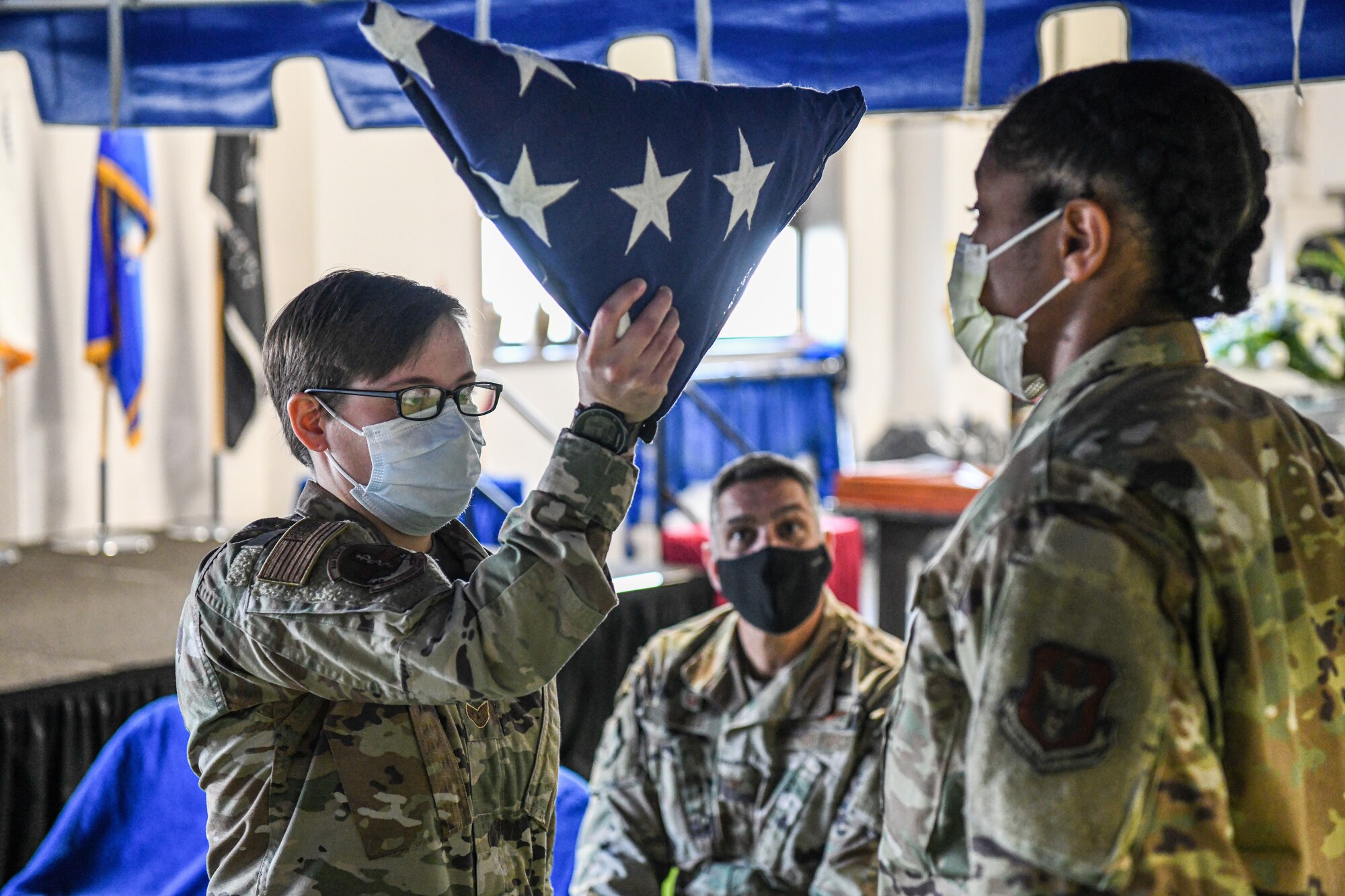 Staff Sgt. Molly Cook, 88th Aerospace Medicine Squadron dental technician and honor guard member, passes a folded U.S. flag to Senior Airman Sharnita Lloyd, 88th Aerospace Medicine Squadron administration apprentice and honor guard member, during a military funeral honors demonstration observed by Col. Raymond A. Smith, 445th Airlift Wing commander, along with other 445th AW commanders at Wright-Patterson Air Force Base, Ohio Dec. 4, 2021.