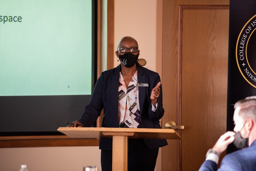 A masked woman speaks at a podium.