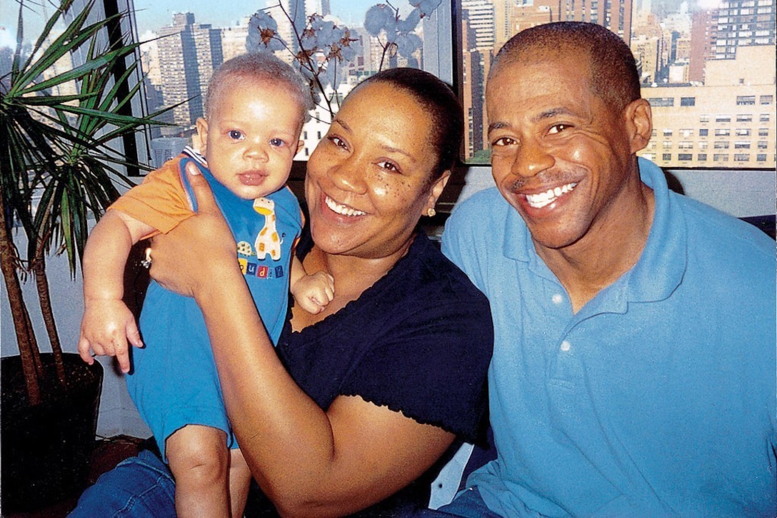 A woman holds a baby. A man is seated next to her.