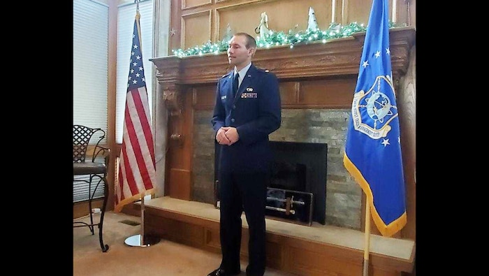 Travis Deckert stands by himself in between the American flag and U.S. Air Force flag while he addresses his family and friends.