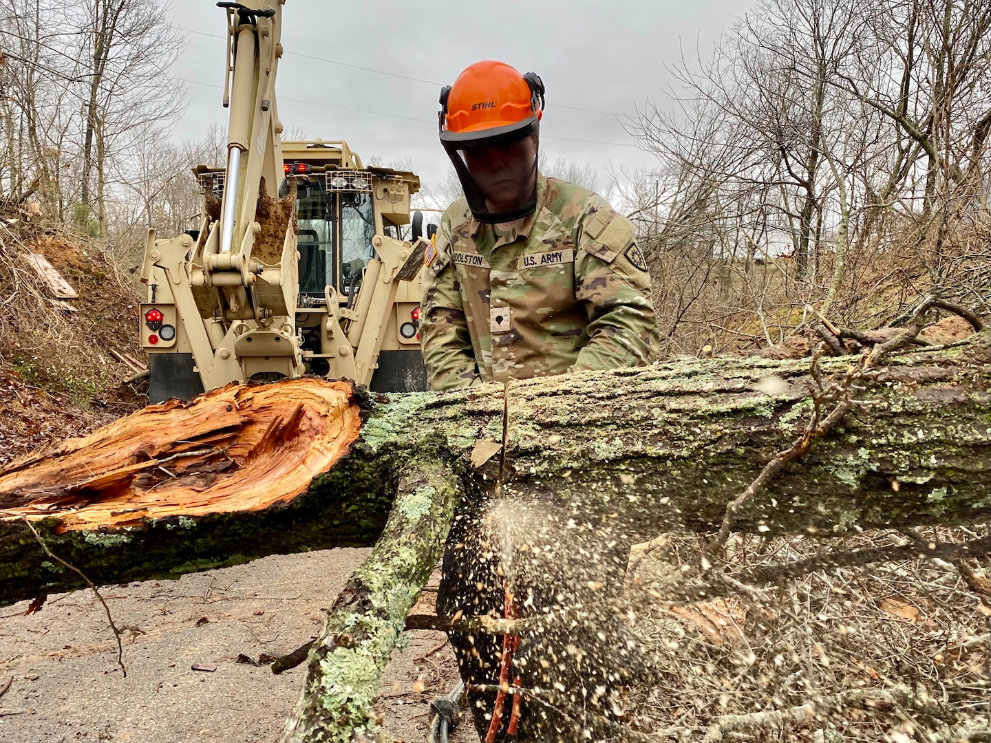 Spc. Dakotah Woolston, with the Kentucky National Guard's 2061st Multi-Role Bridge Company, works to clear a tree from a road in Dawson Springs, Kentucky, Dec. 18, 2021.