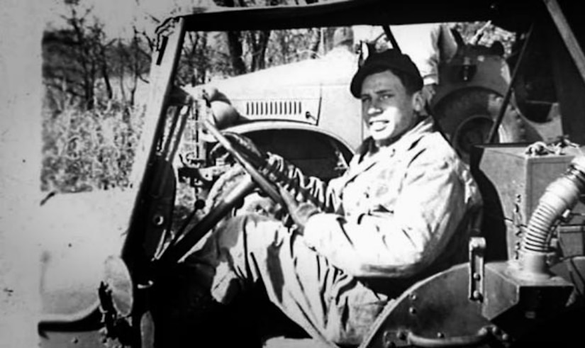 A man poses for a photo in a jeep.