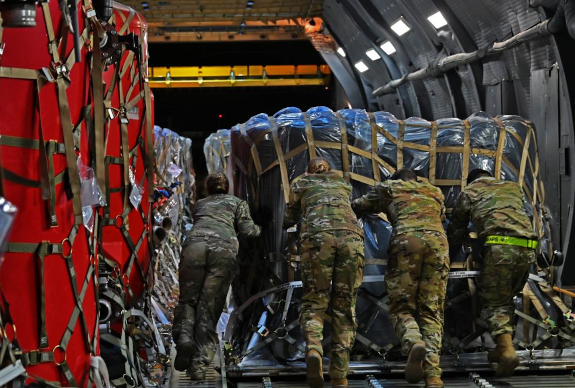 Airmen from the 305th Aerial Port Squadron secure a pallet of water filtration system equipment onto a C-5M Super Galaxy.