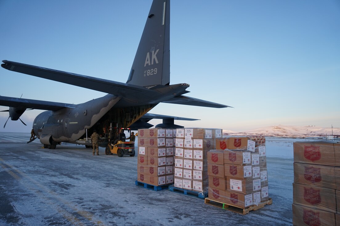 Members for the 176th Wing, Alaska Air National Guard unload pallets of gifts from an HC-130J Combat King II aircraft Dec. 2, 2021, at Nome, Alaska, before they are loaded onto an CH-47 Chinook helicopter for further delivery to Buckland as part of Operation Santa Claus 2021. Op Santa is an Alaska National Guard annual community outreach program that provides gifts, books, school supplies and stocking stuffers to children in rural Alaskan communities. This year marks the 66th year of the program, which began in 1956 after the village of St. Mary's experienced a year of hardship and the Alaska Air National Guard flew in gifts and supplies donated by the local community. The Alaska National Guard was able to continue the tradition this year and safely provide gifts despite COVID-19. (U.S. Army National Guard photo by Dana Rosso/Released).