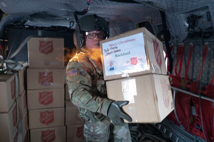 Sgt. Craig Lyons, crewchief, Alaska Army National Guard, B Company, 2-211 General Suppor Aviation Battalion,  helps unload two hundred sixety-one gift packagesfrom a CH-47 Chinook helicopter in Buckland, Alaska during Operation Santa Claus, Dec. 14, 2021. Operation Santa Claus is an Alaska National Guard annual community outreach program that provides Christmas gifts, books, school supplies and stocking stuffers to children in rural Alaskan communities. This year marks the 66th year of the program, which began in 1956 after the village of St. Mary's experienced a year of hardship and the Alaska Air National Guard flew in gifts and supplies donated by the local community. The Alaska National Guard was able to continue the tradition this year and safely provide gifts despite COVID-19. (U.S. Air National Guard photo by Maj. Chelsea Aspelund)