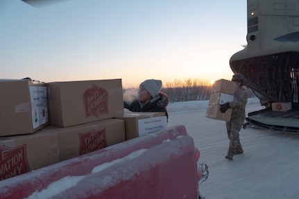 Residents team up with Alaska Army National Guard soldiers to unload two hundred sixety-one gift packages from a CH-47 Chinook helicopter in Buckland, Alaska during Operation Santa Claus, Dec. 14, 2021. Operation Santa Claus is an Alaska National Guard annual community outreach program that provides Christmas gifts, books, school supplies and stocking stuffers to children in rural Alaskan communities. This year marks the 66th year of the program, which began in 1956 after the village of St. Mary's experienced a year of hardship and the Alaska Air National Guard flew in gifts and supplies donated by the local community. The Alaska National Guard was able to continue the tradition this year and safely provide gifts despite COVID-19. (U.S. Air National Guard photo by Maj. Chelsea Aspelund)
