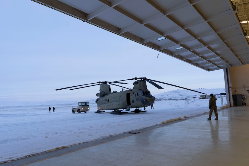 Alaka Army Natiolal Guard CH-47 Chinook helicopter is towed into a hangar at Nome Dec. 14, 2021 after successful gift delivery to Buckland as part of Operation Santa Claus 2021. Op Santa is an Alaska National Guard annual community outreach program that provides Christmas gifts, books, school supplies and stocking stuffers to children in rural Alaskan communities. This year marks the 66th year of the program, which began in 1956 after the village of St. Mary's experienced a year of hardship and the Alaska Air National Guard flew in gifts and supplies donated by the local community. The Alaska National Guard was able to continue the tradition this year and safely provide gifts despite COVID-19. (U.S. Air National Guard photo by Maj. Chelsea Aspelund/Released).