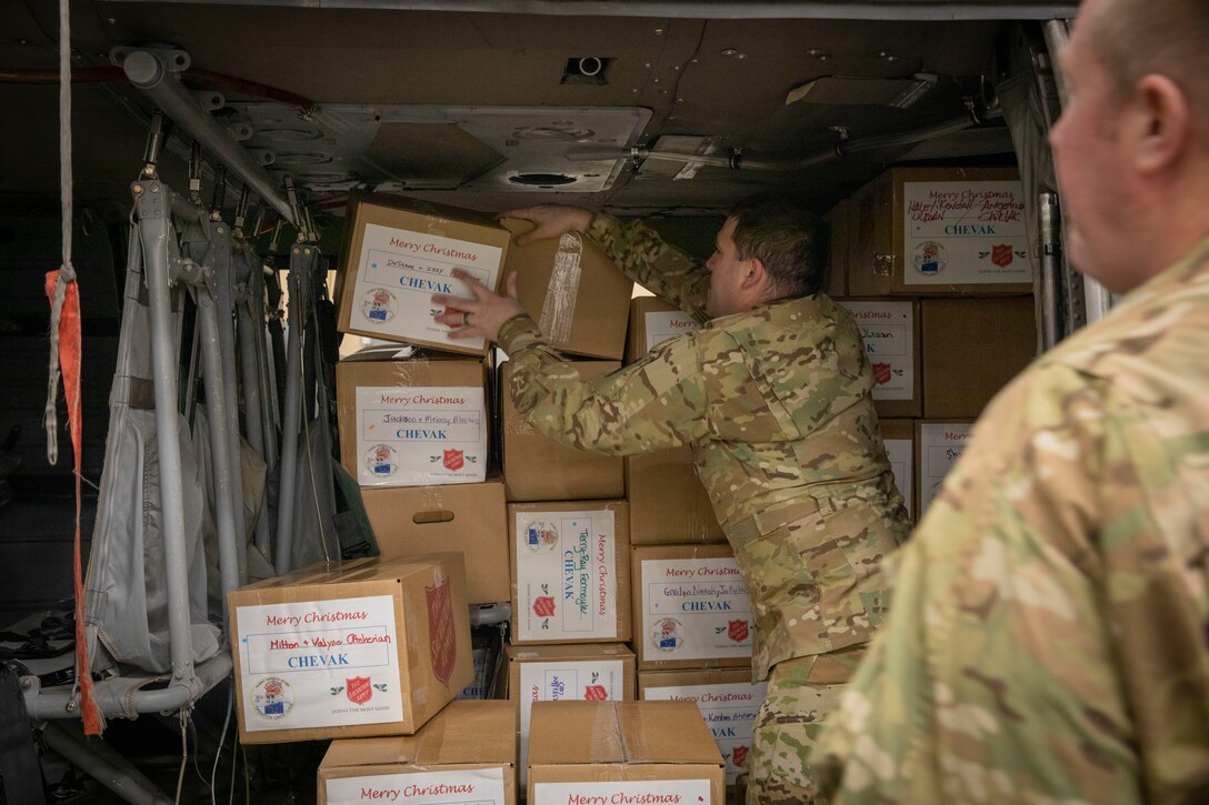 Alaska Army National Guard Capt. Andrew Adams and Chief Warrant Officer 2 Bryan Kruse load pallets of gifts onto an UH-60 Black Hawk helicopter Dec. 13 at the Army Aviation Facility in Bethel, for further delivery to Chevak as part of Operation Santa Claus 2021. Op Santa is an Alaska National Guard annual community outreach program that provides Christmas gifts, books, school supplies and stocking stuffers to children in rural Alaskan communities. This year marks the 65th year of the program, which began in 1956 after the village of St. Mary's experienced a year of hardship and the Alaska Air National Guard flew in gifts and supplies donated by the local community. The Alaska National Guard was able to continue the tradition this year and safely provide gifts despite COVID-19. (U.S. Army National Guard photo by Spc. Grace Nechanicky).