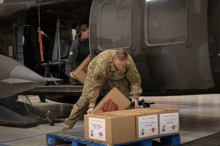 Alaska Army National Guard Capt. Andrew Adams loads pallets of gifts onto an UH-60 Black Hawk helicopter Dec. 13 at the Army Aviation Facility in Bethel, for further delivery to Chevak as part of Operation Santa Claus 2021. Op Santa is an Alaska National Guard annual community outreach program that provides Christmas gifts, books, school supplies and stocking stuffers to children in rural Alaskan communities. This year marks the 65th year of the program, which began in 1956 after the village of St. Mary's experienced a year of hardship and the Alaska Air National Guard flew in gifts and supplies donated by the local community. The Alaska National Guard was able to continue the tradition this year and safely provide gifts despite COVID-19. (U.S. Army National Guard photo by Spc. Grace Nechanicky).