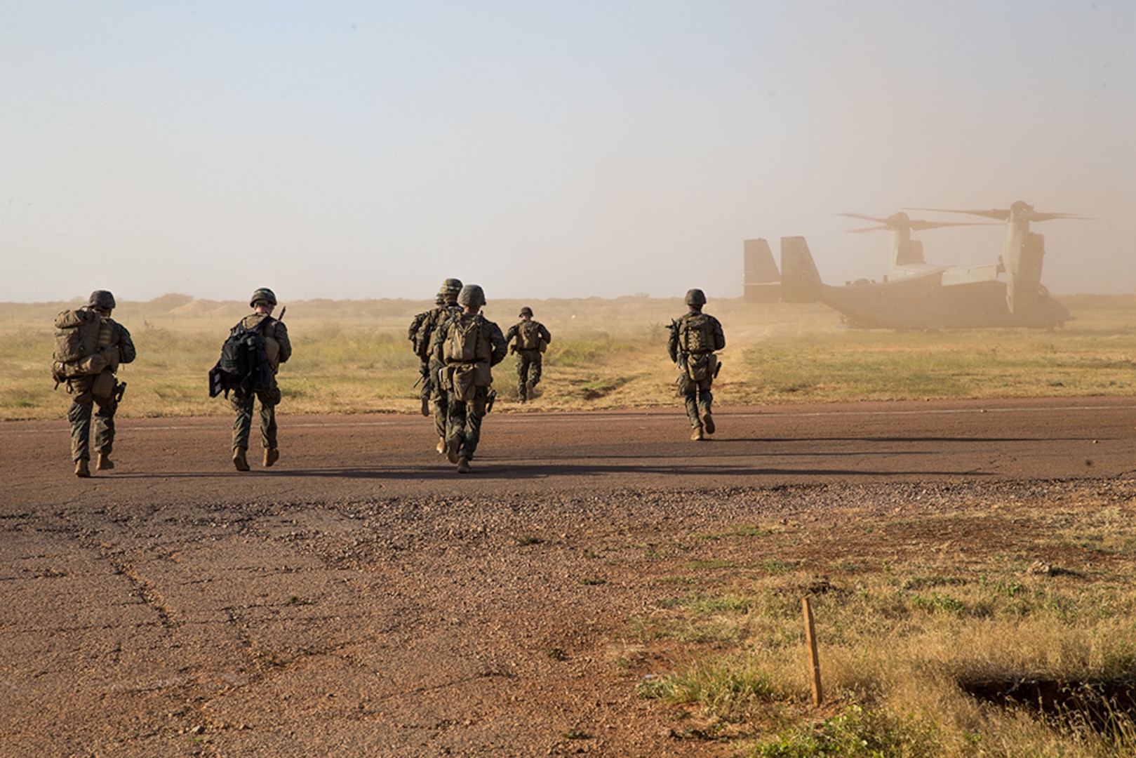 Marines walk toward an Osprey tilt-rotor aircraft.