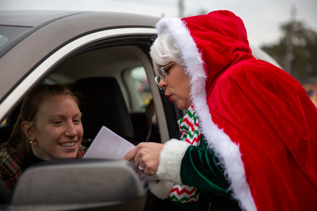 Nicole Blosser, an event volunteer, greets a family during the Home for the Holidays drive-thru event at the Knox Community Center on Marine Corps Base Camp Lejeune, North Carolina, Dec. 9, 2021.