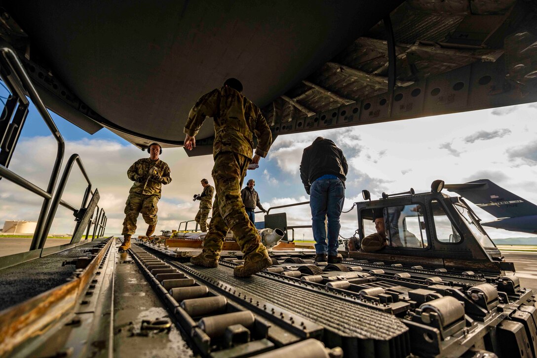 Airmen load military equipment onto an aircraft.