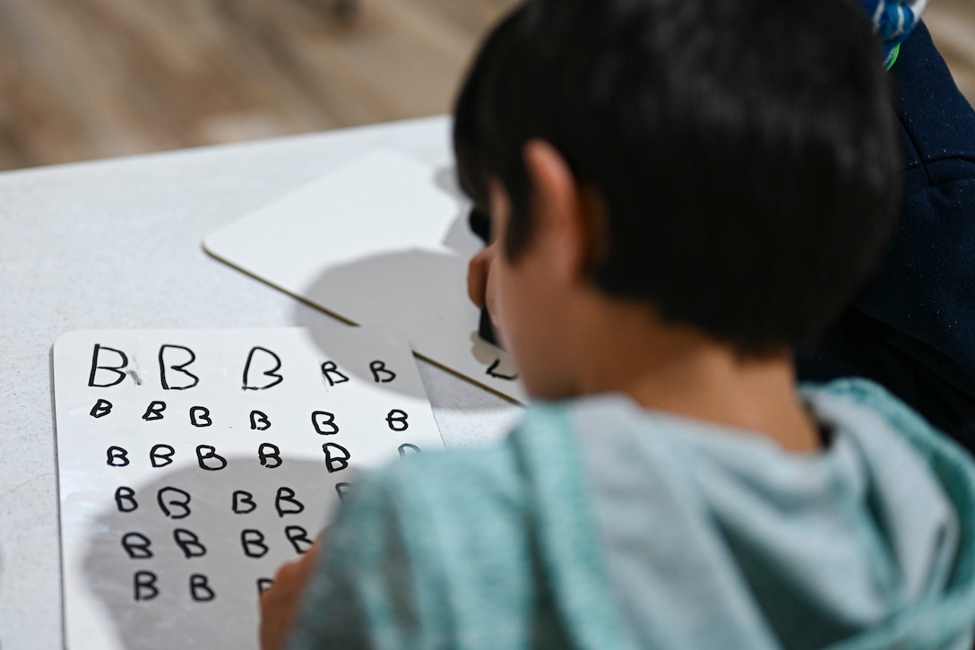 A child writes out letters.