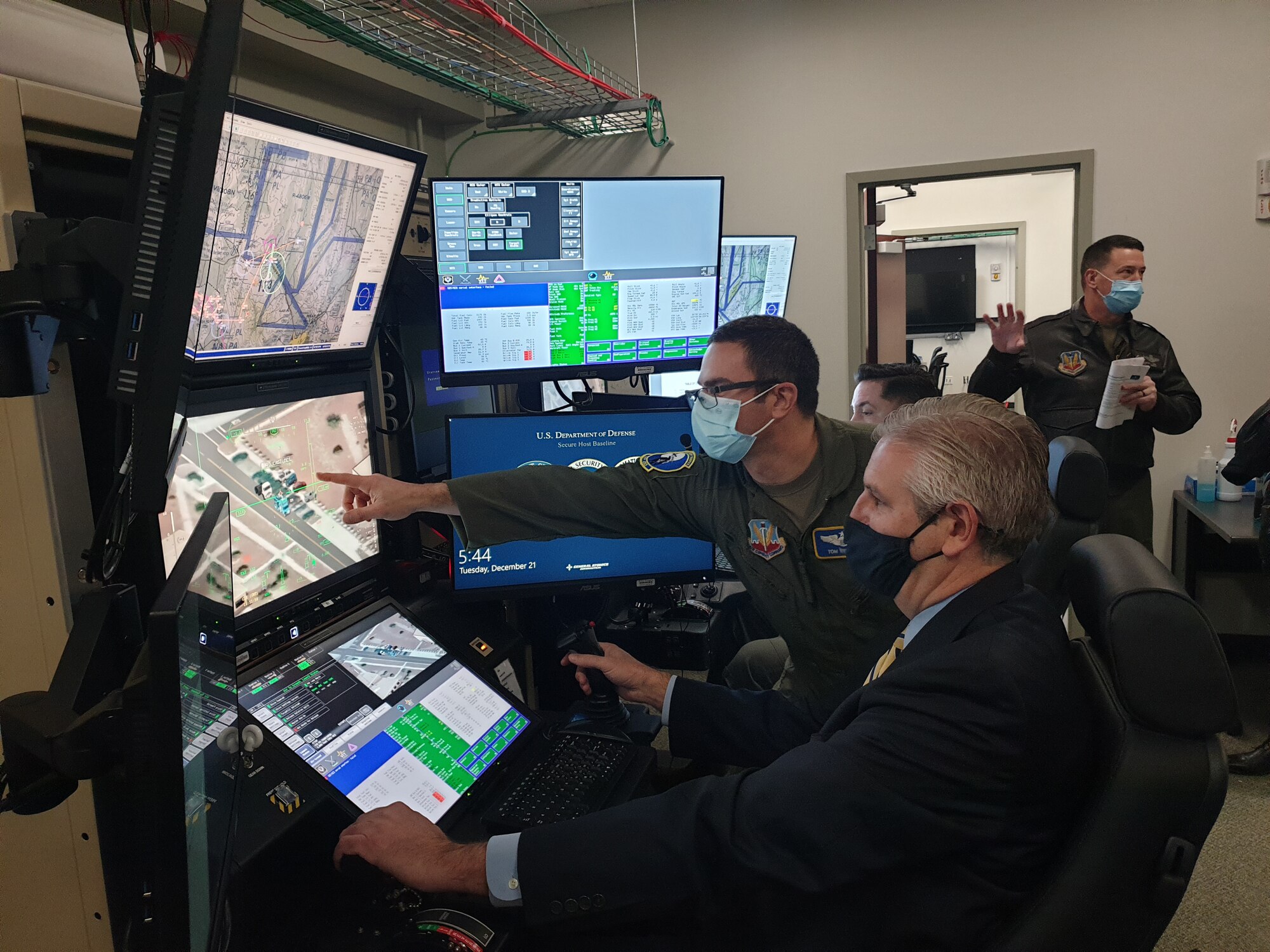 A civilian is shown the controls on a U.S. Air Force MQ-9 Reaper Simulator.