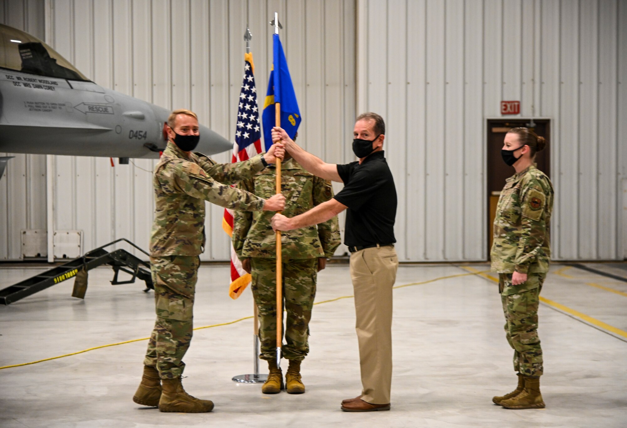 Tim Keating, 8th Aircraft Maintenance Unit site lead, passes the guidon to Col. Thomas Preston, 49th Maintenance Group commander, during the 8th AMU transition ceremony, Dec. 22, 2021, on Holloman Air Force Base, New Mexico. The addition of over 200 8th AMU positions makes the 849th Aircraft Maintenance Squadron the largest squadron in the 49th Wing. (U.S. Air Force photo by Airman 1st Class Jessica Sanchez-Chen)
