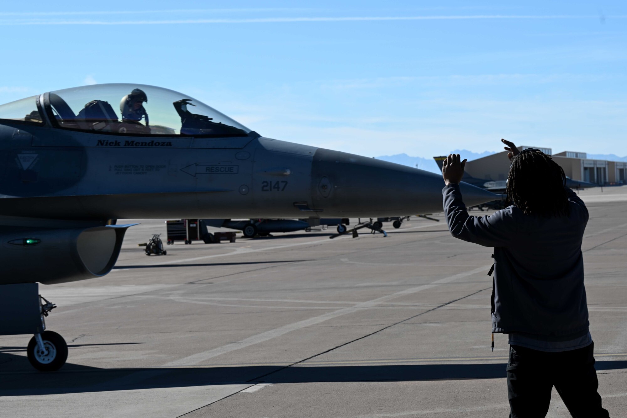 A civilian contractor, assigned to the 8th Aircraft Maintenance Unit, marshals out an F-16 Viper to taxi, Dec. 22, 2021, on Holloman Air Force Base, New Mexico. In 2017, civilian contractors assumed the responsibility of 8th Fighter Squadron aircraft with the reactivation of the 8th AMU. (U.S. Air Force photo by Staff Sgt. Christopher S. Sparks)