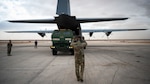 A loadmaster marshals a high mobility artillery rocket system into a C-130J super hercules.