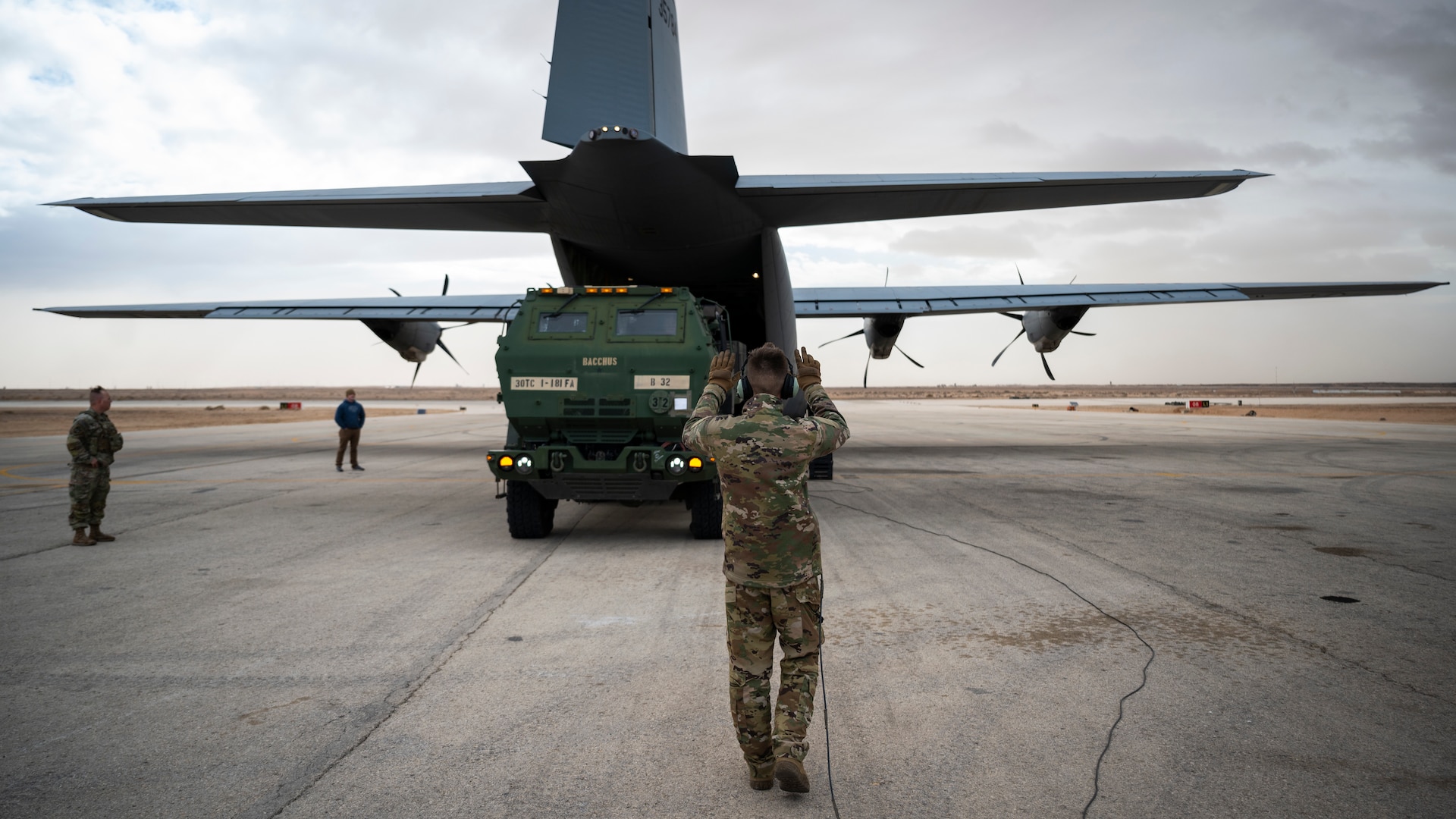 A loadmaster marshals a high mobility artillery rocket system into a C-130J super hercules.