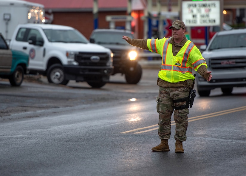 Airman 1st Class Jayden Guthrie of the Kentucky Air National Guard’s 123rd Security Forces Squadron directs traffic in Mayfield, Ky., Dec. 18, 2021. Guthrie and 16 other security forces Airmen mobilized from Louisville, Ky., to augment the Mayfield Police Department following a Category 5 tornado that leveled much of the town. (U.S. Air National Guard photo by Staff Sgt. Clayton Wear)